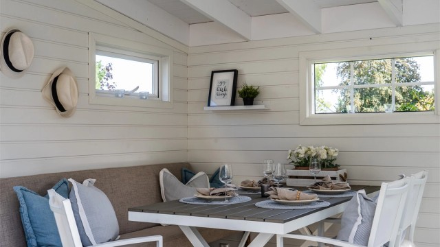 Frittstående utestue innredet med langbord og sittebenk for hyggelige sommerkvelder.
