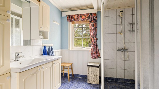 Baderommet er utstyrt med wc, servant, skap og dusjhjørne.