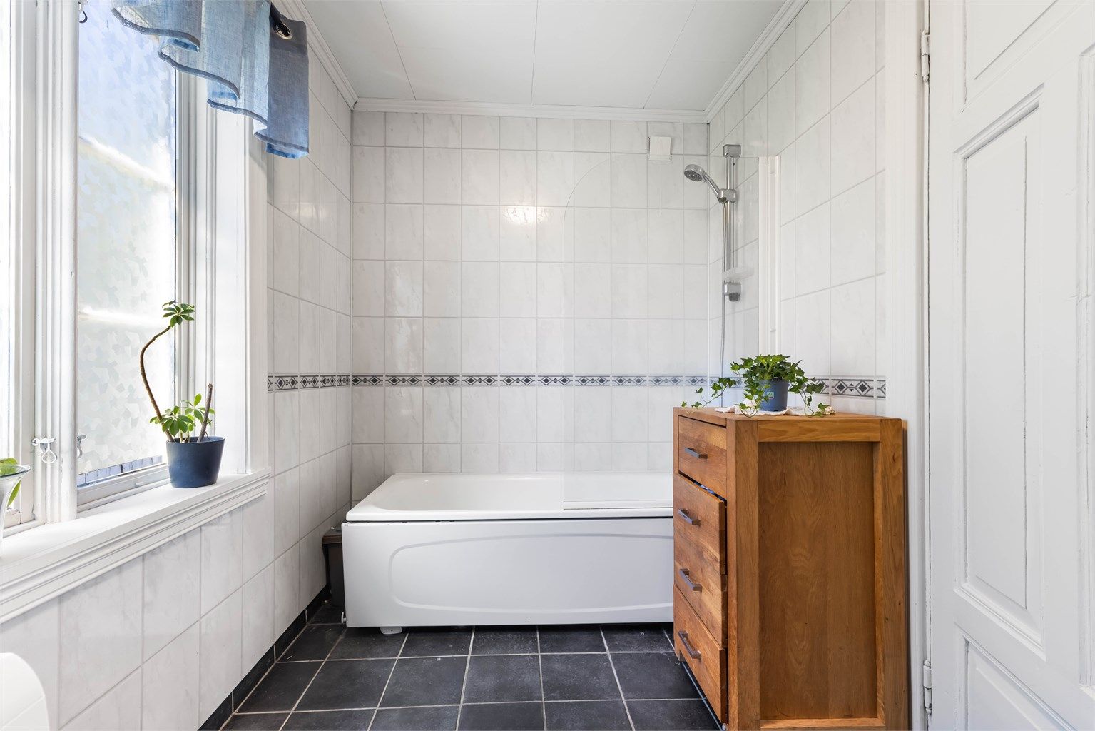 Baderommet er innredet med badekar og har mekanisk avtrekksvifte i veggen.