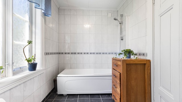 Baderommet er innredet med badekar og har mekanisk avtrekksvifte i veggen.