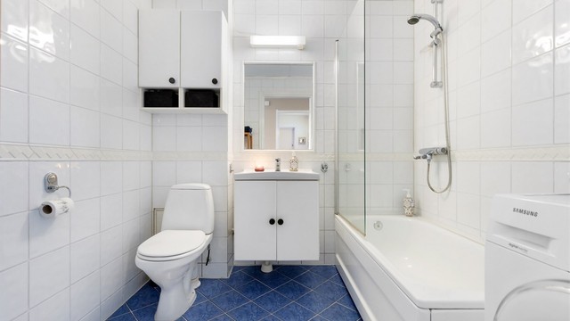 Baderom med fliser på gulv med gulvvarme, fliser på vegger og malt betonghimling