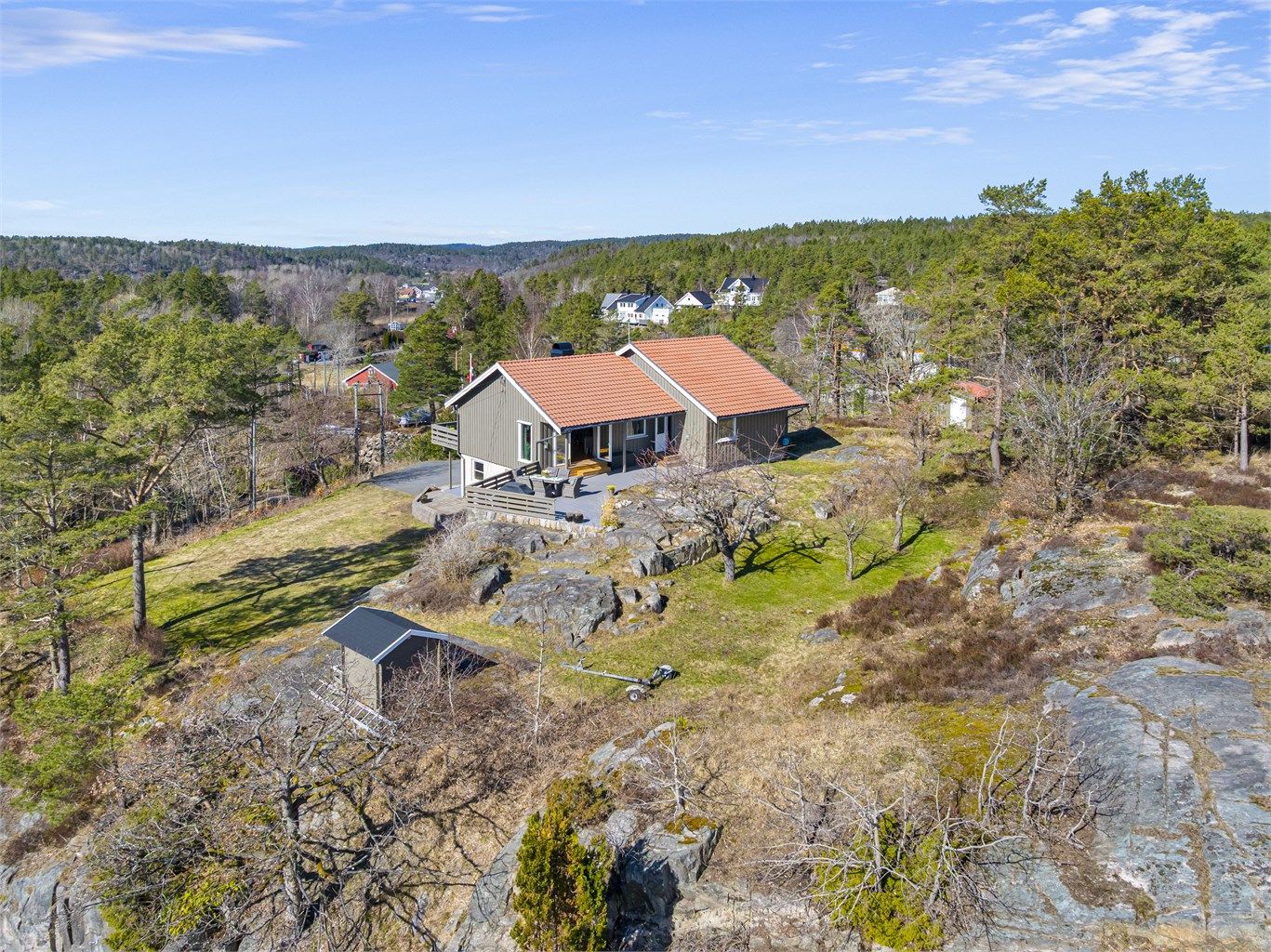 Tomten er preget av svaberg og natur, og gir en usjenert ramme rundt boligen. På eiendommen står også en frittstående garasje på 28 m², oppført i 1986.
