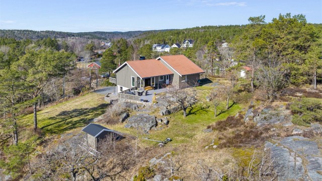 Tomten er preget av svaberg og natur, og gir en usjenert ramme rundt boligen. På eiendommen står også en frittstående garasje på 28 m², oppført i 1986.