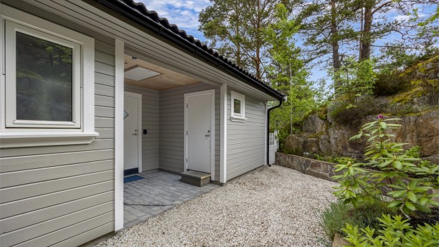 Hytta har fasader kledd med liggende trekledning. Her er også inngang til en utvendig bod.