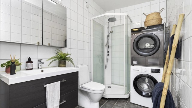 Flislagt bad med gulvvarme, dusjkabinett og opplegg for vaskemaskin.