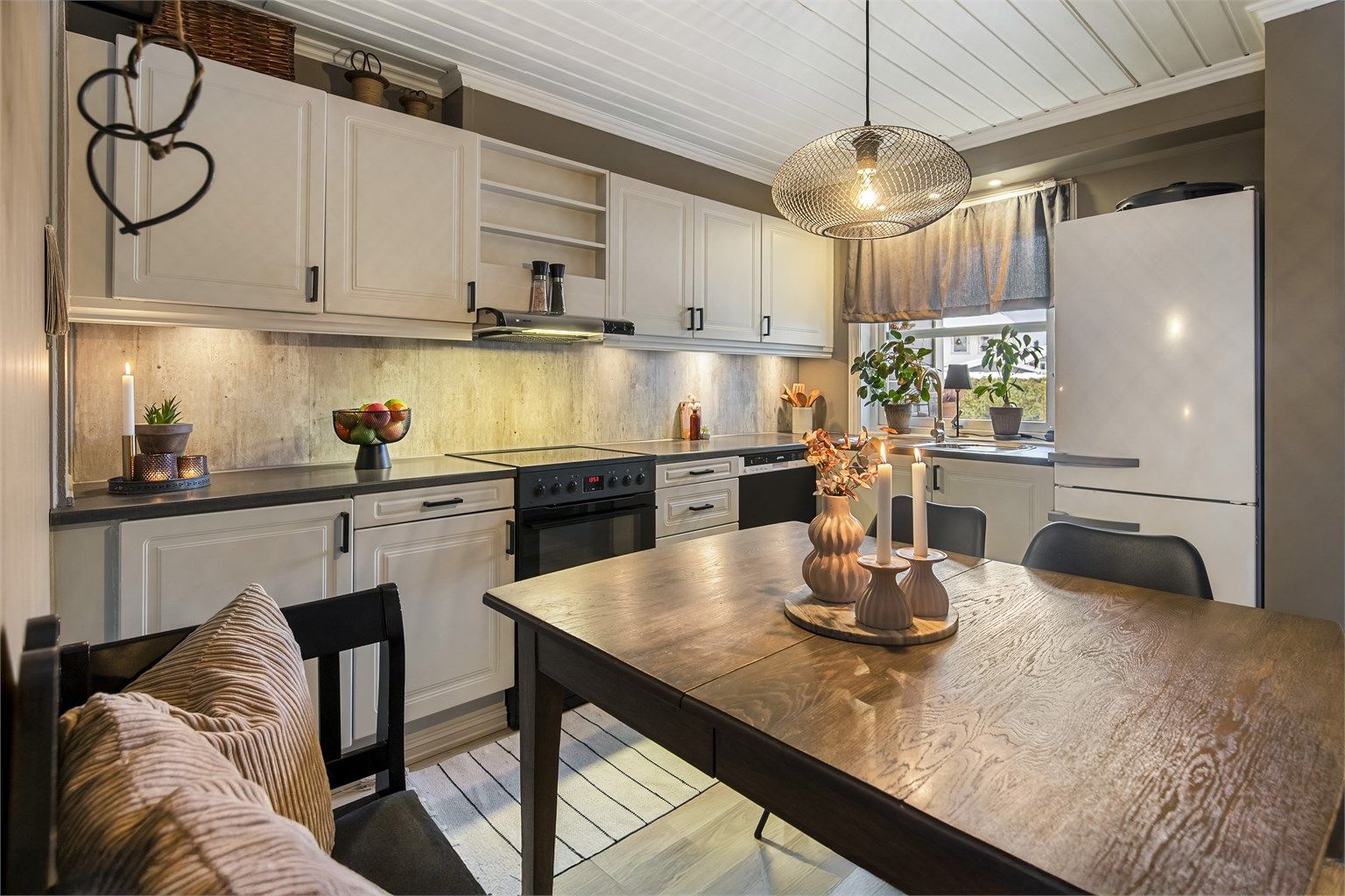 Koselig og innbydende kjøkken med profilerte fronter, sorte detaljer og backsplash på vegg