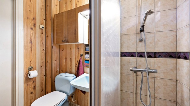 Badet har dusjvegg med skyvedør innredet med flislagte gulv og vegger