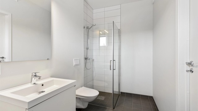 Stilren baderomsinnredning med servant, speil med belysning og stikkontakt.