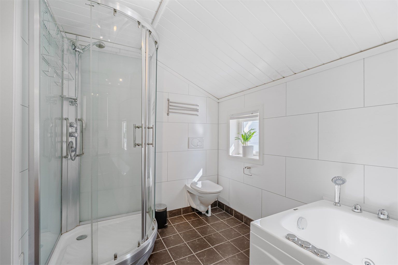 Badet er innredet med dusjkabinett, badekar, wc og servant.