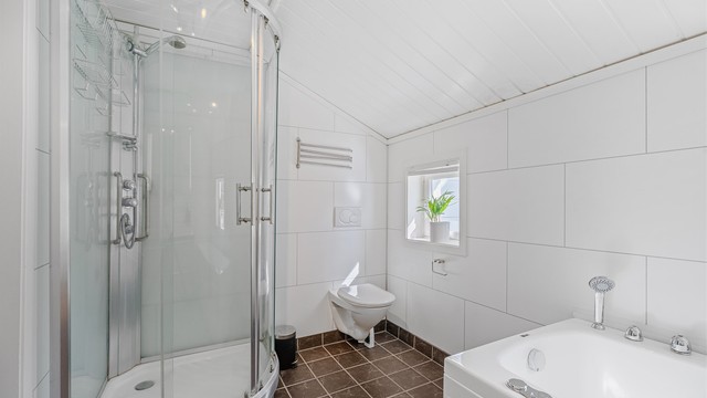 Badet er innredet med dusjkabinett, badekar, wc og servant.