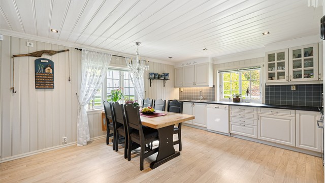 Kjøkkeninnredningen har profilerte fronter samt benkeplate med laminert overflate. Kjøkkenvask med armatur, belysning under overskap og stikkontakter over benkeplaten gir en praktisk arbeidsplass.