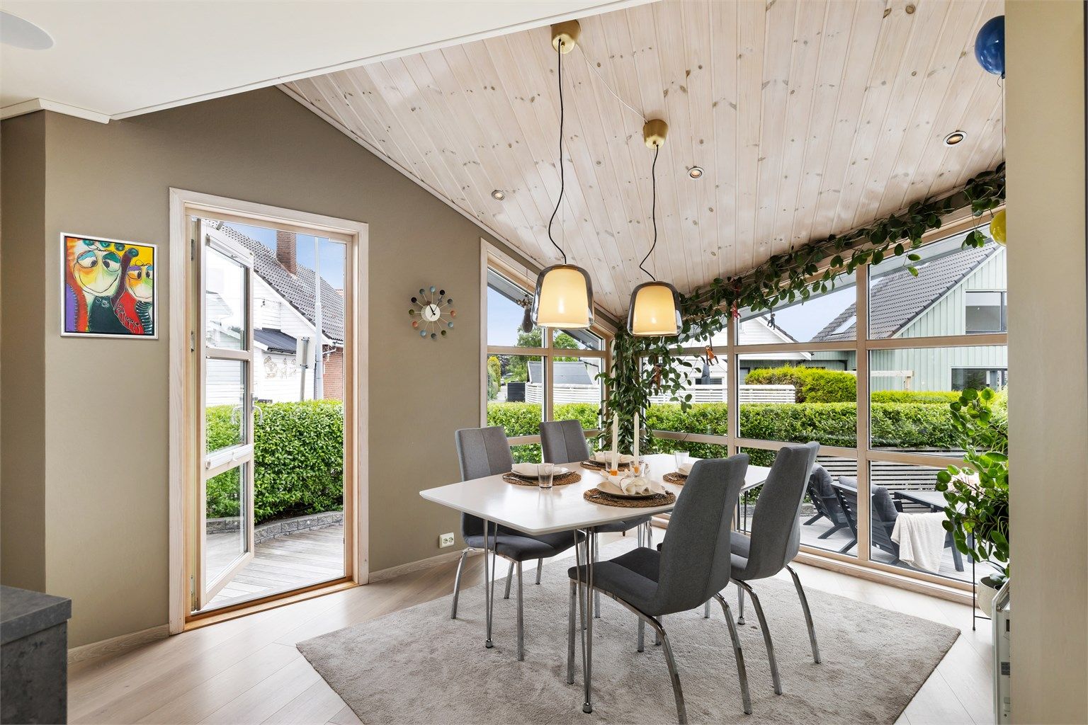 Store vindusflater gir rikelig med naturlig lys til spiseplassen. Her er det utgang til terrasse og uteplass på fremsiden av boligen.
