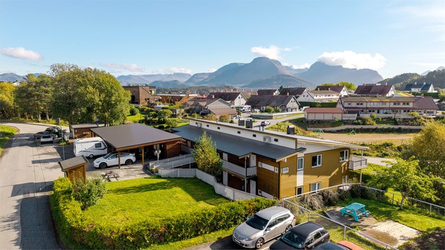 Etablert boligmiljø med felles plen, lekeområde og storslått utsikt mot Sunnmørsalpene.