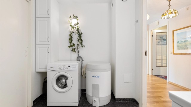 God plass til både vaskemaskin og ekstra oppbevaring på dette romslige badet. Skyvedøren til venstre er ikke i bruk i dag, men leder til soverom/bibliotek.