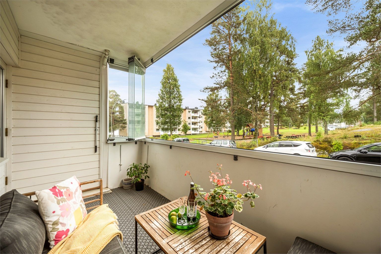Sydvendt og romslig innglasset balkong med luftig utsyn mot fellesområdet og lekeplassen.