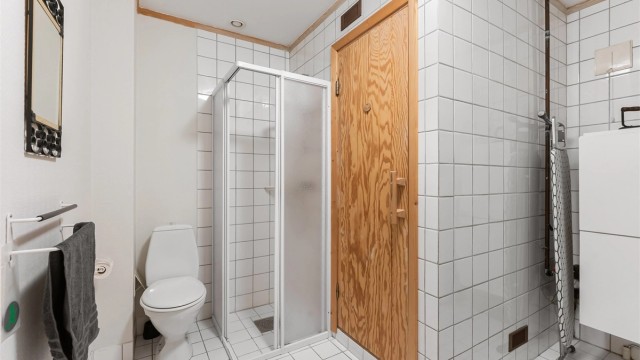 Bad/vaskerom i underetasjen med flislagt gulv med gulvvarme, dusjhjørne og opplegg for vaskemaskin.