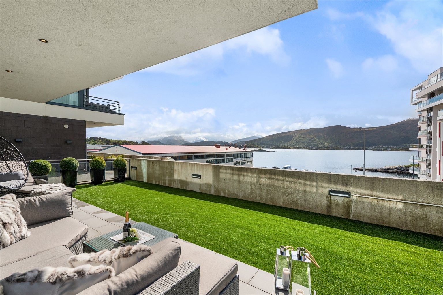 Sydvendt flislagt markterrasse og hage/uteområde belagt med kunstgress på hele 91 kvm! Flott utsikt mot fjord og fjell