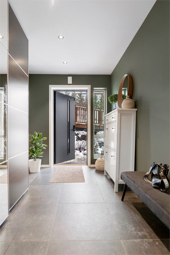Velkommen inn i en flislagt entré med skyvedørsgarderobe