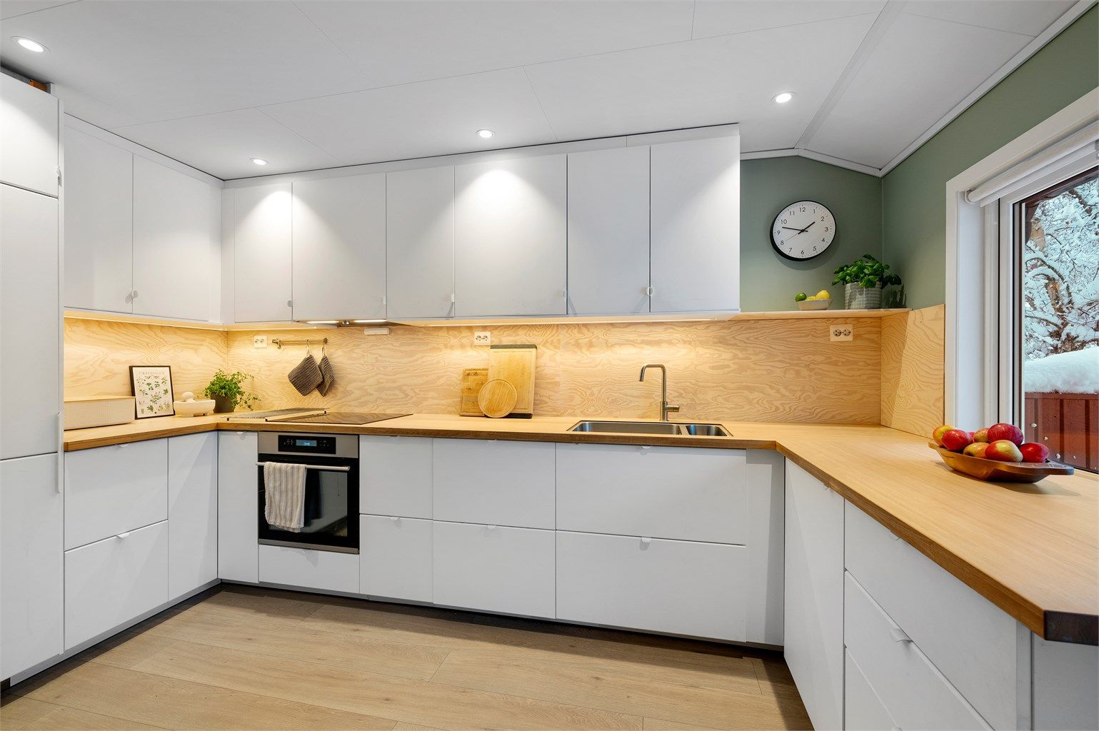 Nydelig, tilbaketrukket IKEA-kjøkken med lyse slette flater og benkeplate av ask/finer.