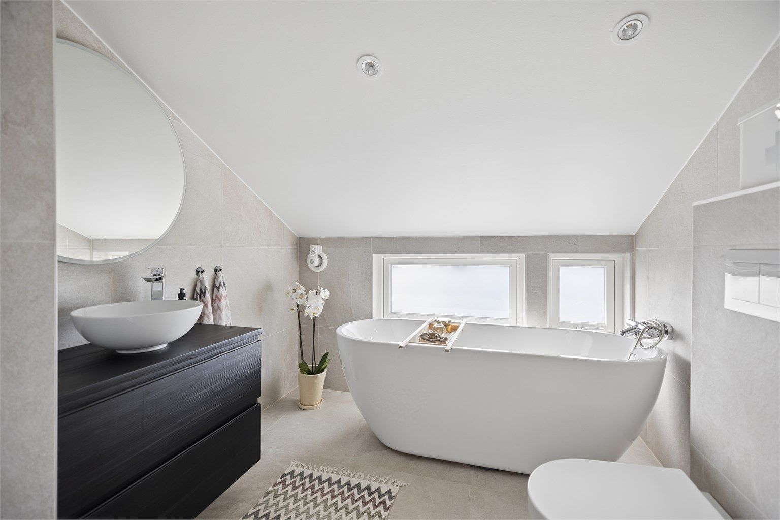 Lekkert, flislagt bad oppgradert i 2020. Badet fremstår som moderne og innbydende  med badekar, dusjhjørne, servantinnredning  og vegghengt toalett.