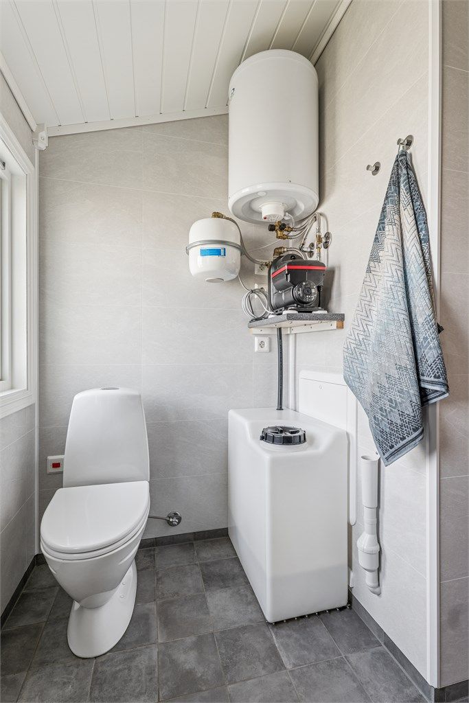 På badet finner vi også vanntanken, varmtvannsberederen og pumpen som sørger for kontinuerlig vanntrykk.