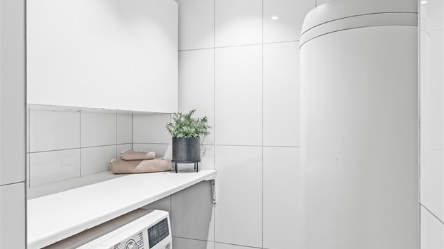 Vaskeromsnisjen har opplegg for vaskemaskin, benkeplass og overskap. Her er også boligens 300-liters varmtvannsbereder plassert.