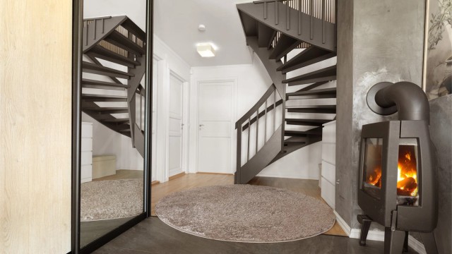 Praktisk skyvedørsgarderobe med speildører og peisovn som varmer etasjen.