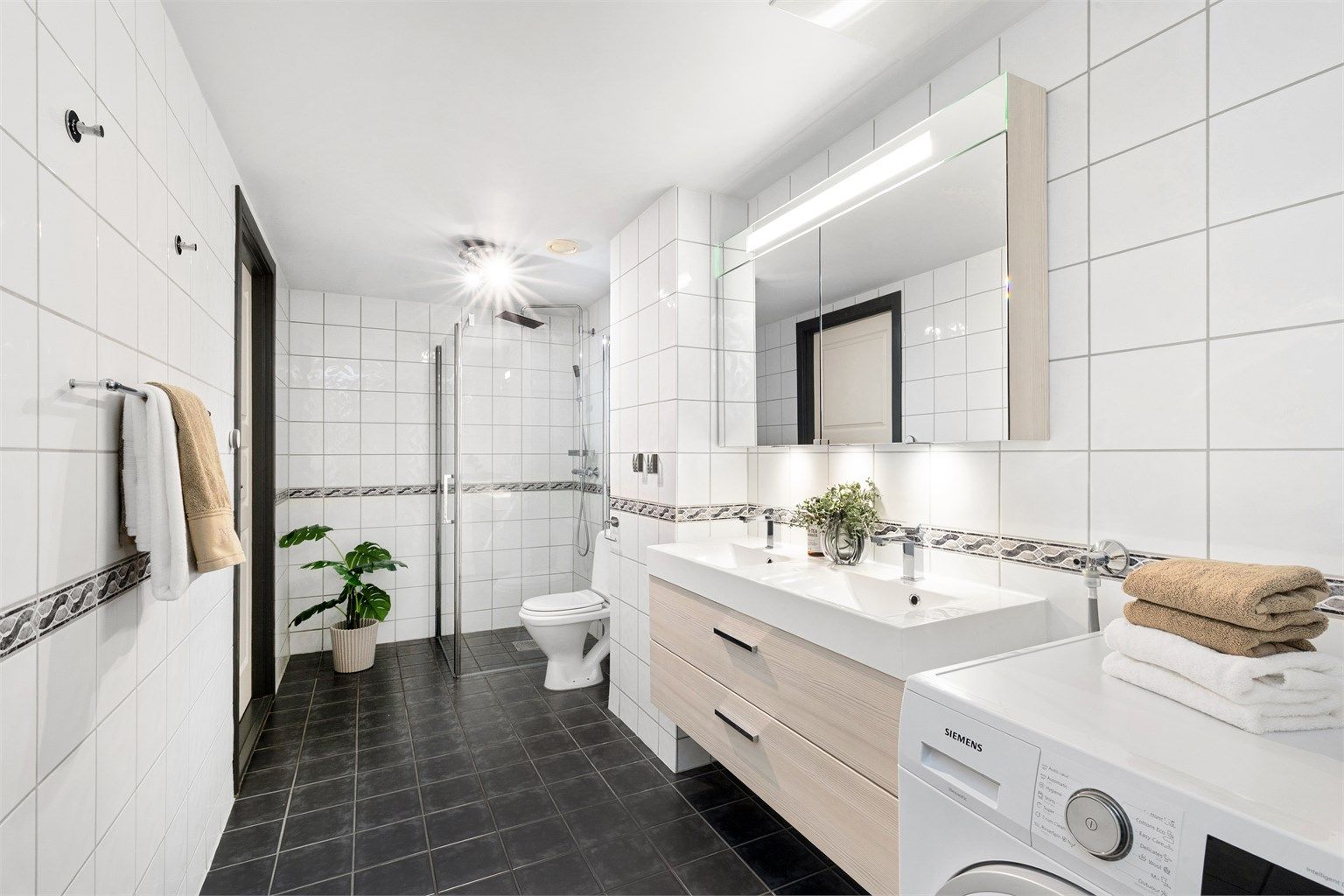 Baderommet er tidløst og flislagt fra byggeåret, og har gulvvarme. Innredning, speilskap, dusjhjørne og armaturer ble oppgradert i 2013.