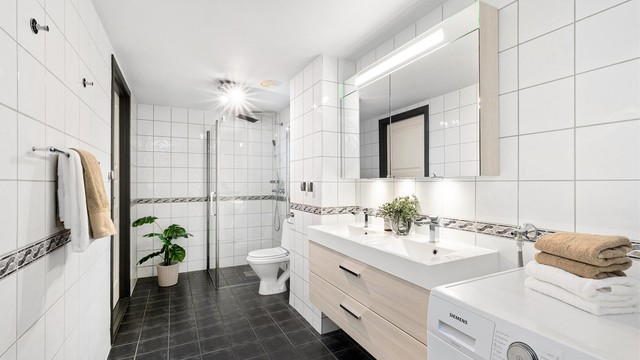 Baderommet er tidløst og flislagt fra byggeåret, og har gulvvarme. Innredning, speilskap, dusjhjørne og armaturer ble oppgradert i 2013.