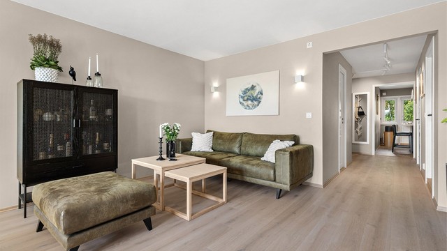 Romslig stue med plass til sittegrupper, TV-område og spisebord.