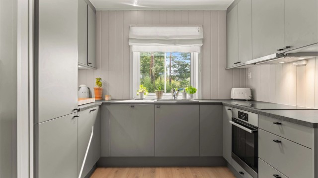 Kjøkkenet har en moderne innredning med glatte fronter og benkeplate i laminat. Her finner du godt med oppbevaringsplass og praktiske løsninger.
