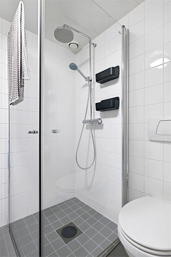 Badet er innredet med dusjhjørne, glassdører og veggmontert toalett.