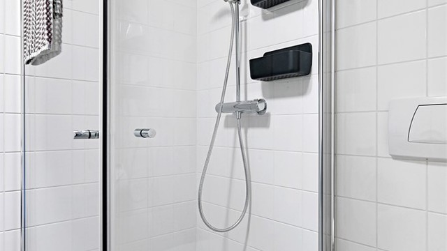 Badet er innredet med dusjhjørne, glassdører og veggmontert toalett.