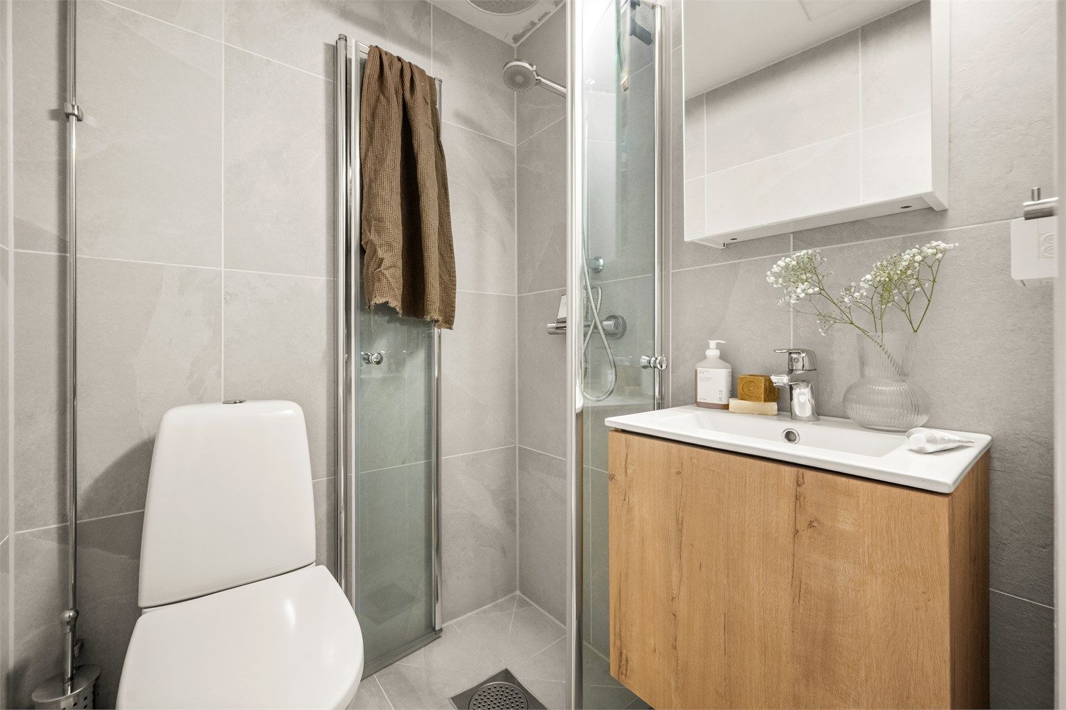 Innredet med klosett, baderomsinnredning med servant og speilskap med lys.