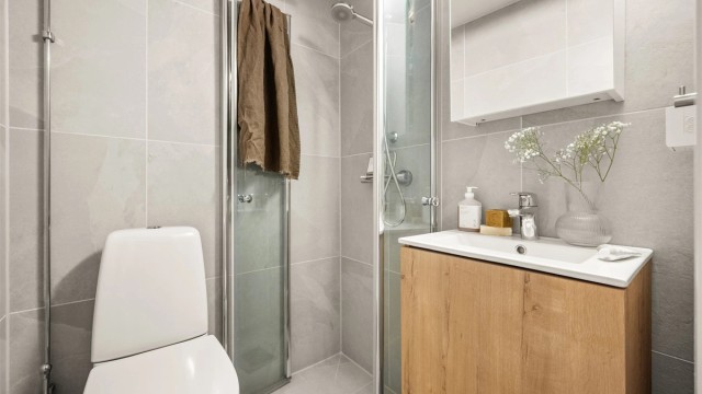 Innredet med klosett, baderomsinnredning med servant og speilskap med lys.