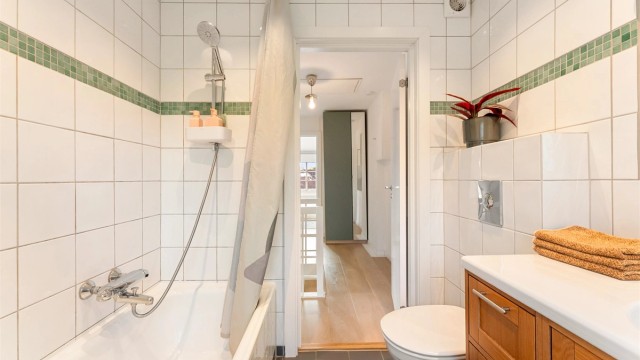 Innredet med baderomsmøbel i treverk med heldekkende servant, speil, toalett og innmurt badekar