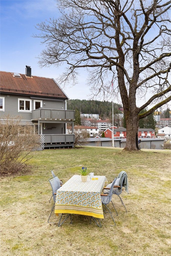 Fellesareal med sjarmerende frukttrær, opparbeidet plen, hellelagte plattinger og flott beplanting. 