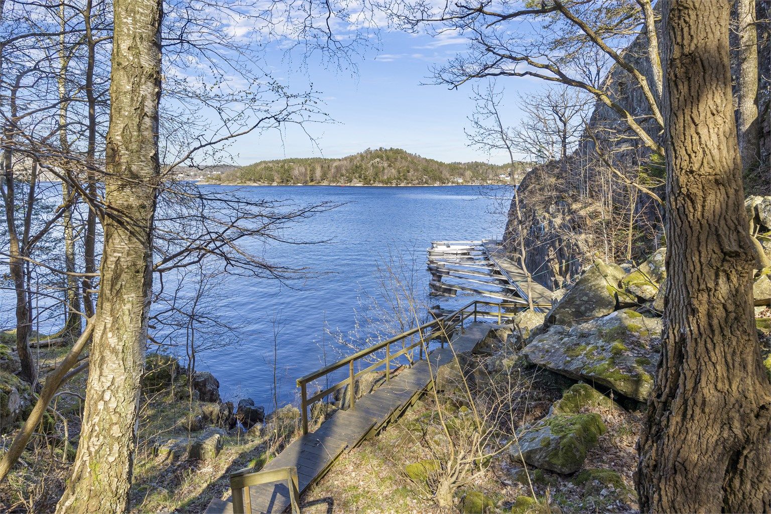 En sti med trapper i tre leder ned til bryggeanlegget og båtplassen. Badestige er det også.