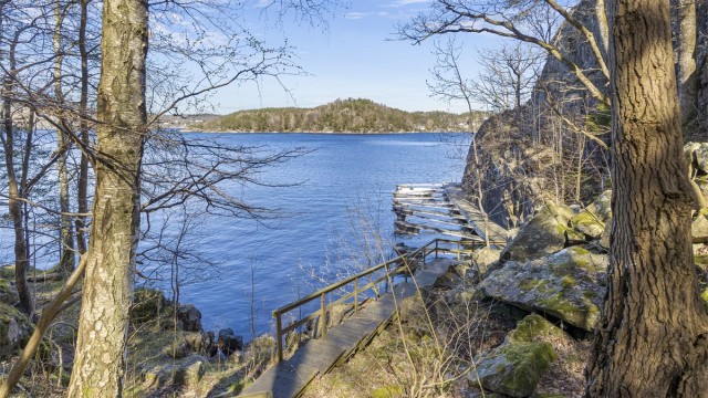 En sti med trapper i tre leder ned til bryggeanlegget og båtplassen. Badestige er det også.