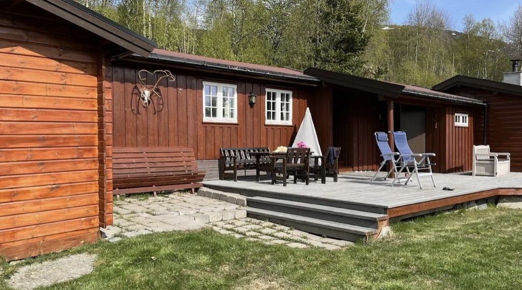Uteområde foran hytten med stor markterrasse med trapp til terrreng