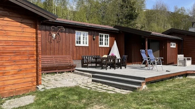 Uteområde foran hytten med stor markterrasse med trapp til terrreng
