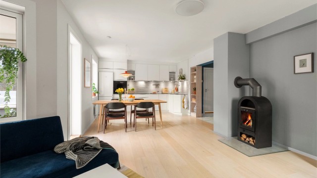 Leiligheten har en åpen og sosial løsning mellom kjøkken og stue, hvor vedovnen skaper ekstra hygge. Foto: Fotostallen v/ Lars-Petter Skillestad