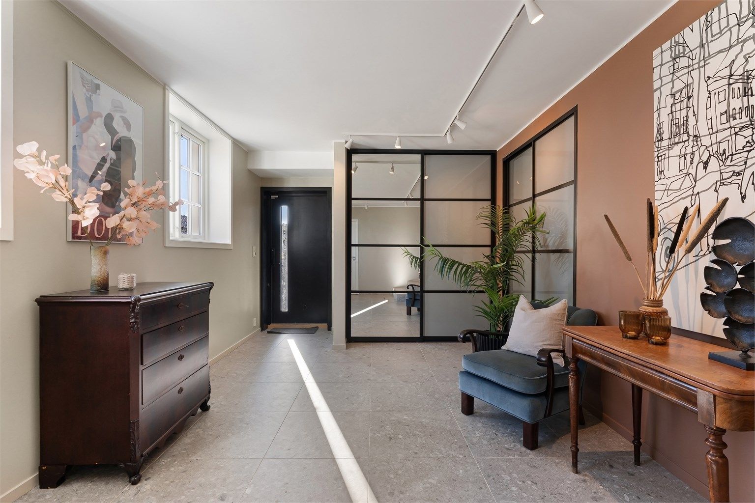 Stor og luftig entrè med flislagt gulv, gulvvarme og smarte integrerte garderobeløsninger. Nyere ytterdør