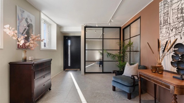 Stor og luftig entrè med flislagt gulv, gulvvarme og smarte integrerte garderobeløsninger. Nyere ytterdør