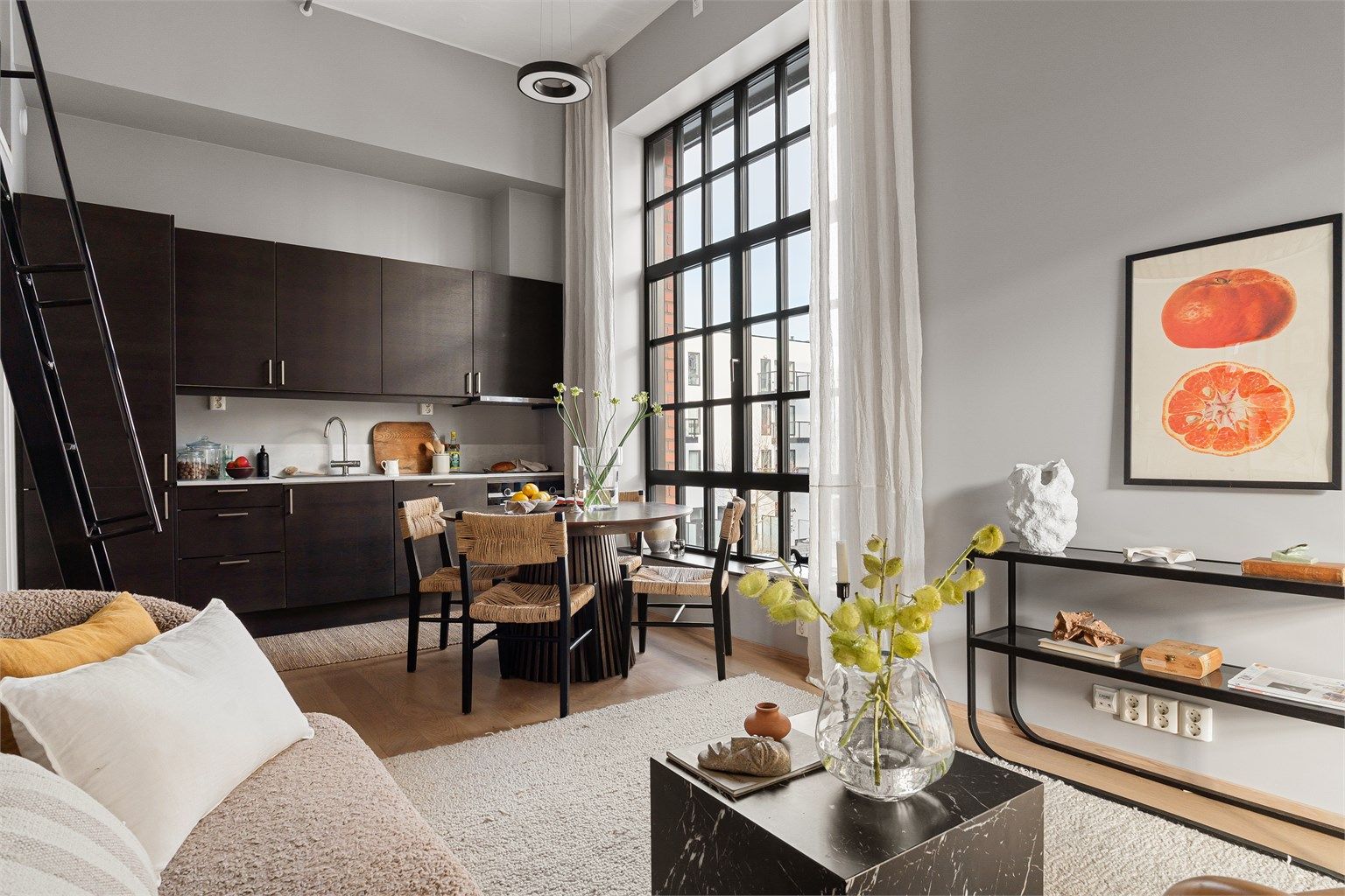 De generøse vindusflatene, kombinert med den åpne planløsningen mot kjøkkenet, skaper en romfølelse utenom det vanlige og gir boligen et tydelig industrielt preg. 