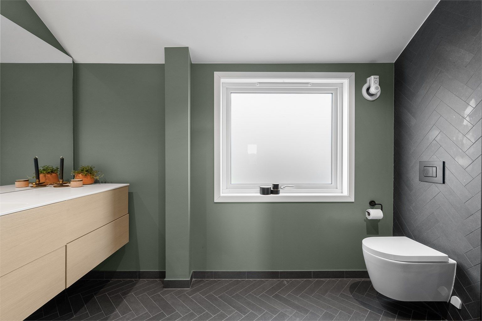 Vegghengt toalett, stor servant med skuffer til oppbevaring og stor speil på vegg Varmekabler i gulv.
Stort vindu, som er av nyere alder. 