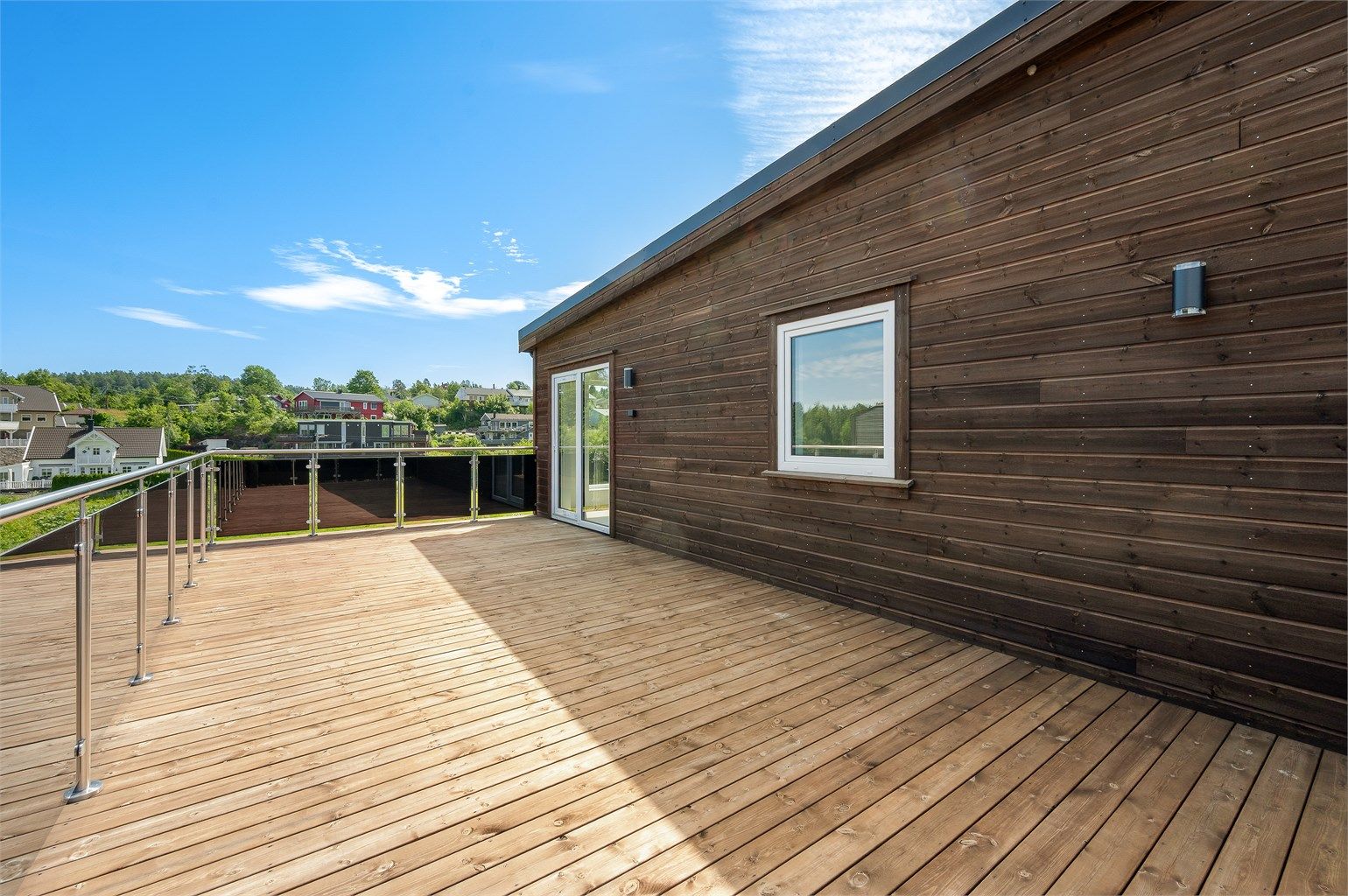 Romslig terrasse med glassrekkverk.  