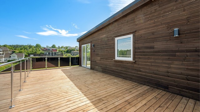 Romslig terrasse med glassrekkverk.