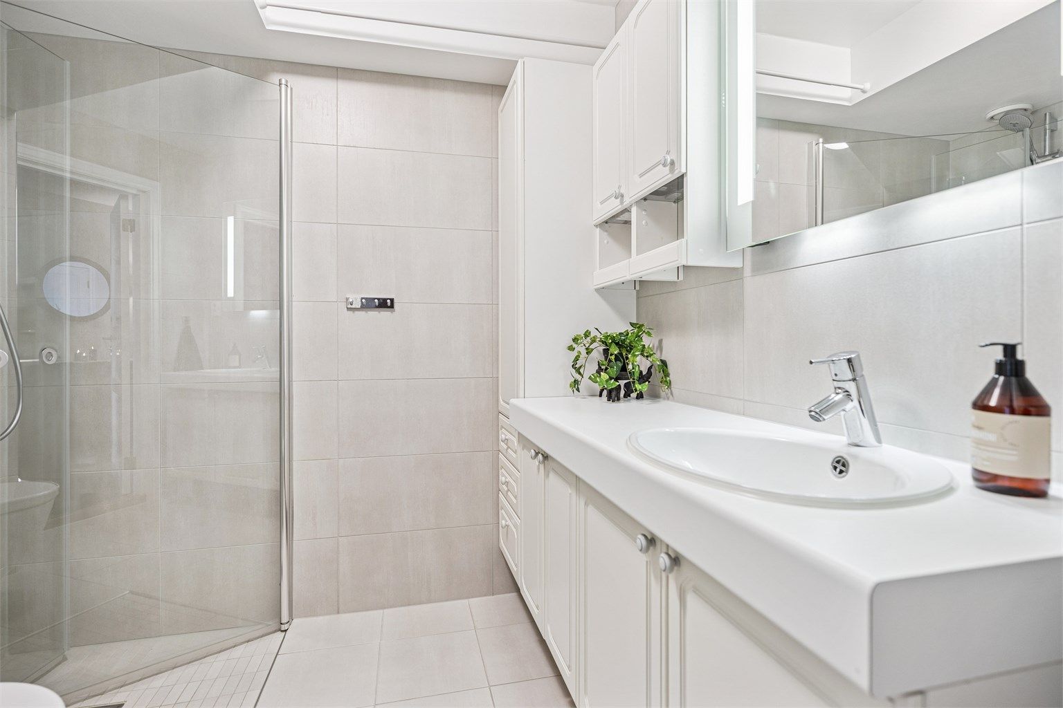 Pent flislagt bad med adkomst fra gangen. Her finner du servantinnredning, vegghengt toalett og dusjhjørne med innfellbare glassdører. 