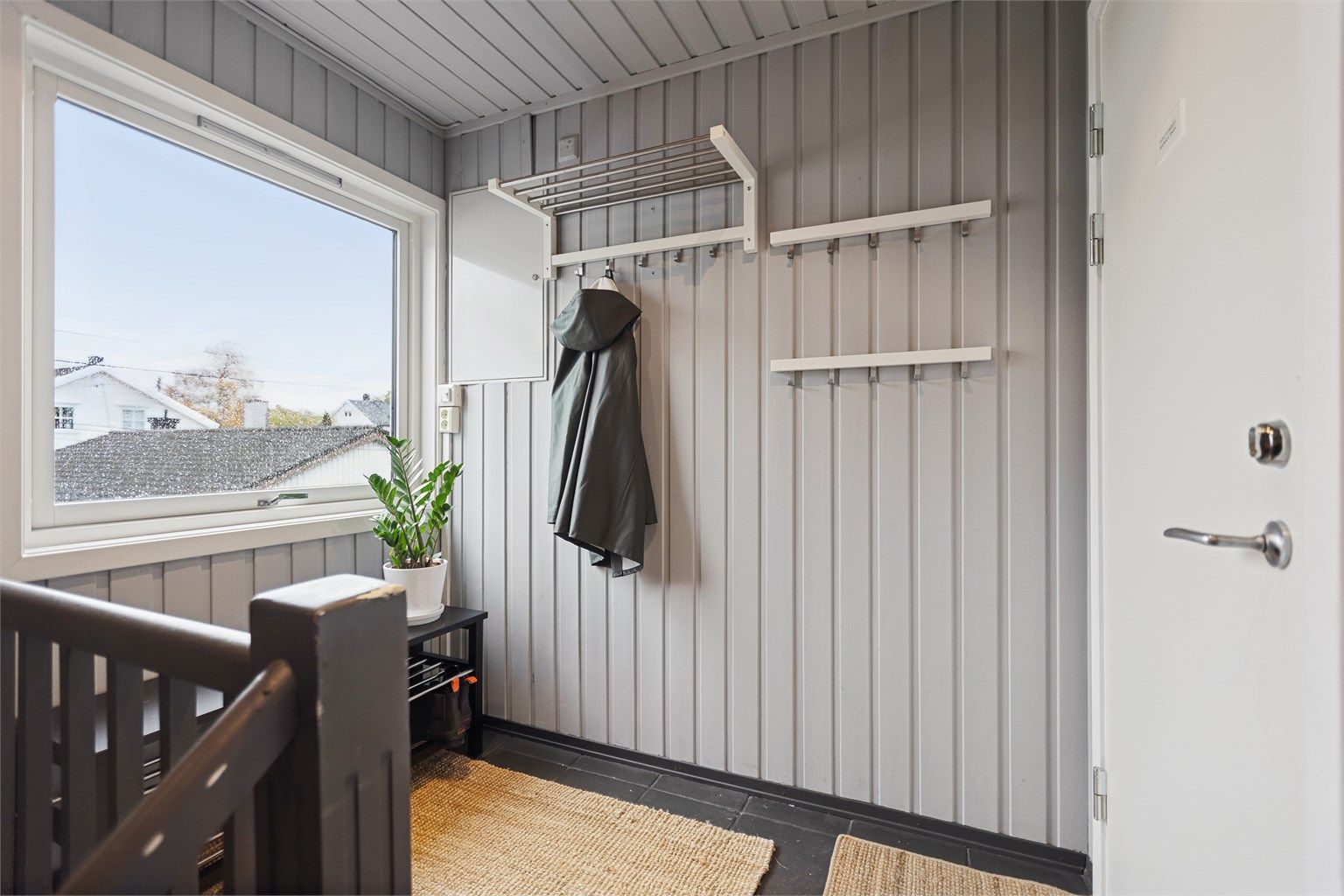 Entré og trapperom med malt panel og plass til yttertøy.(Fellesgang)